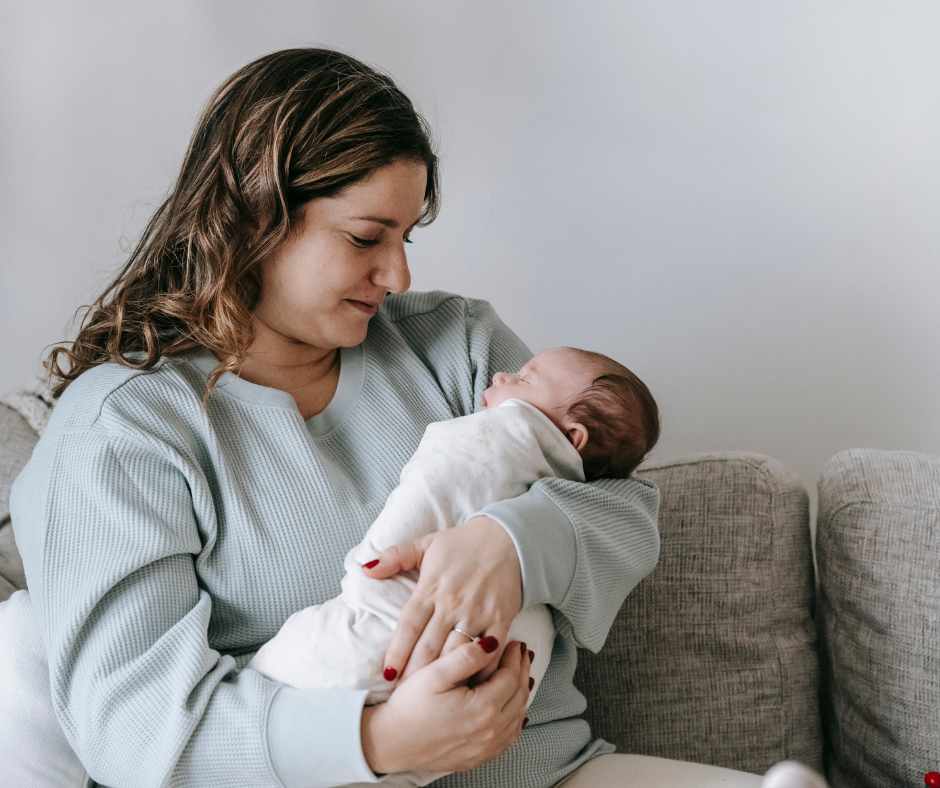 New mum looks down at newborn baby sleeping in her arms.