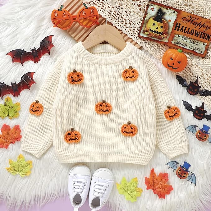 A cream jumper in a baby size is decorated with small halloween pumpkins