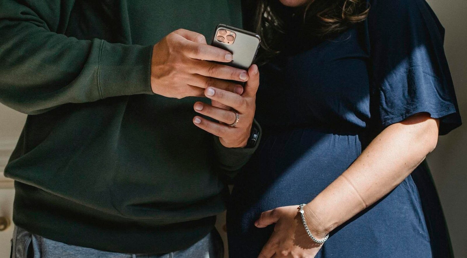 A couple enjoys a tender moment indoors while anticipating parenthood, gently embracing a baby bump.