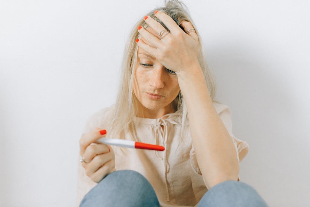 A concerned woman looks at a pregnancy test, reflecting emotions of anxiety and uncertainty.
