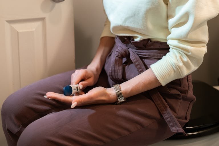A woman anxiously holding a pregnancy test in a bathroom setting, depicting anticipation and emotion.