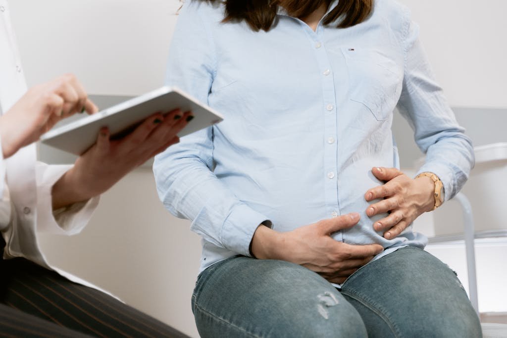 Pregnant woman attending a healthcare consultation, showcasing doctor-patient interaction.