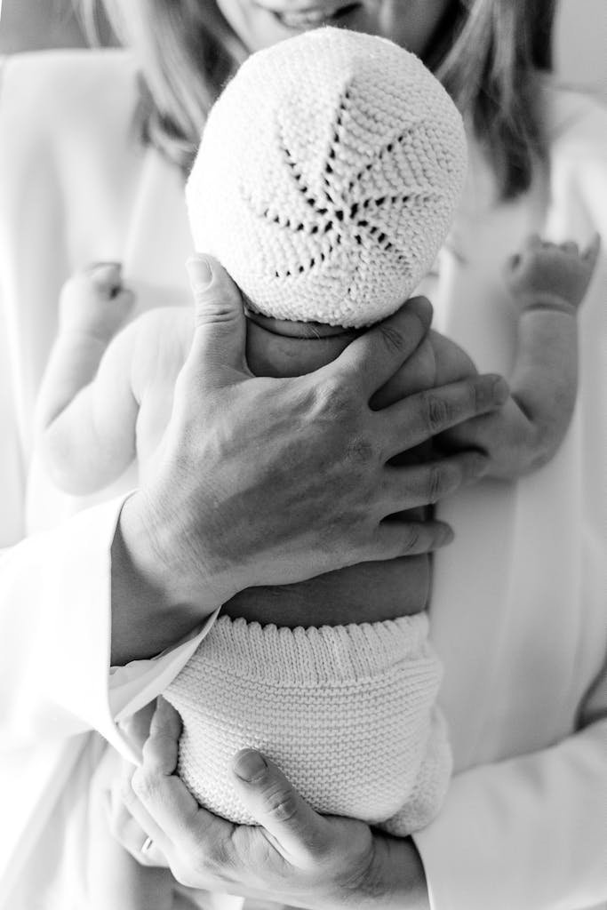 Black and white photo of a mother tenderly holding her newborn baby, showcasing love and bonding.