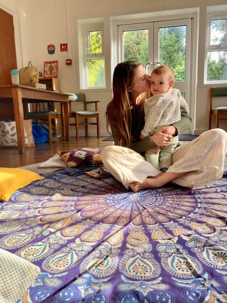 One Positive Birth Story (and how it changed everything) Nicole Harwood and her infant son sit cross legged on a patterned rug.